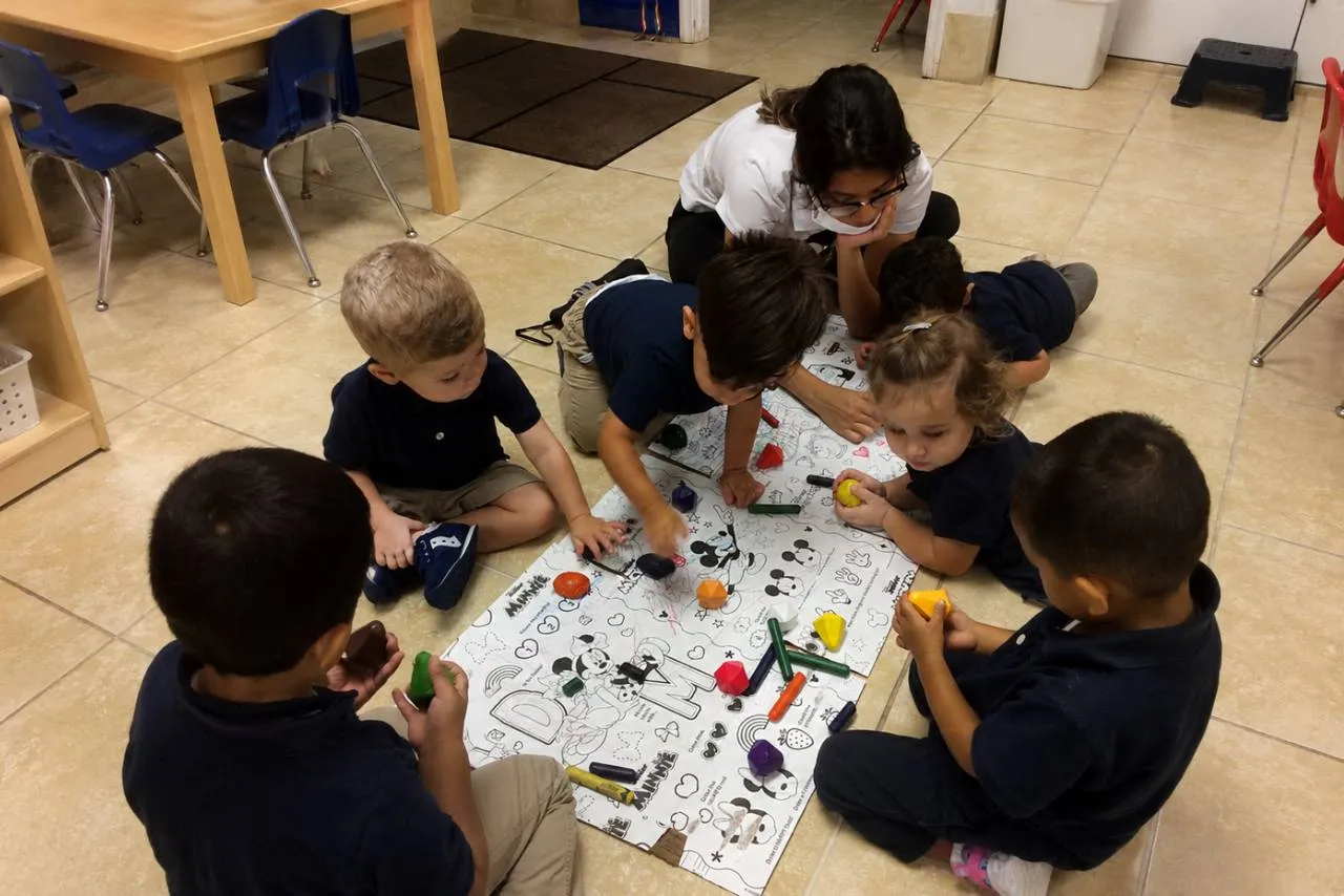 Teacher welcoming a child into the classroom during morning drop-off at Horizons Childcare & Learning Center in Orlando.